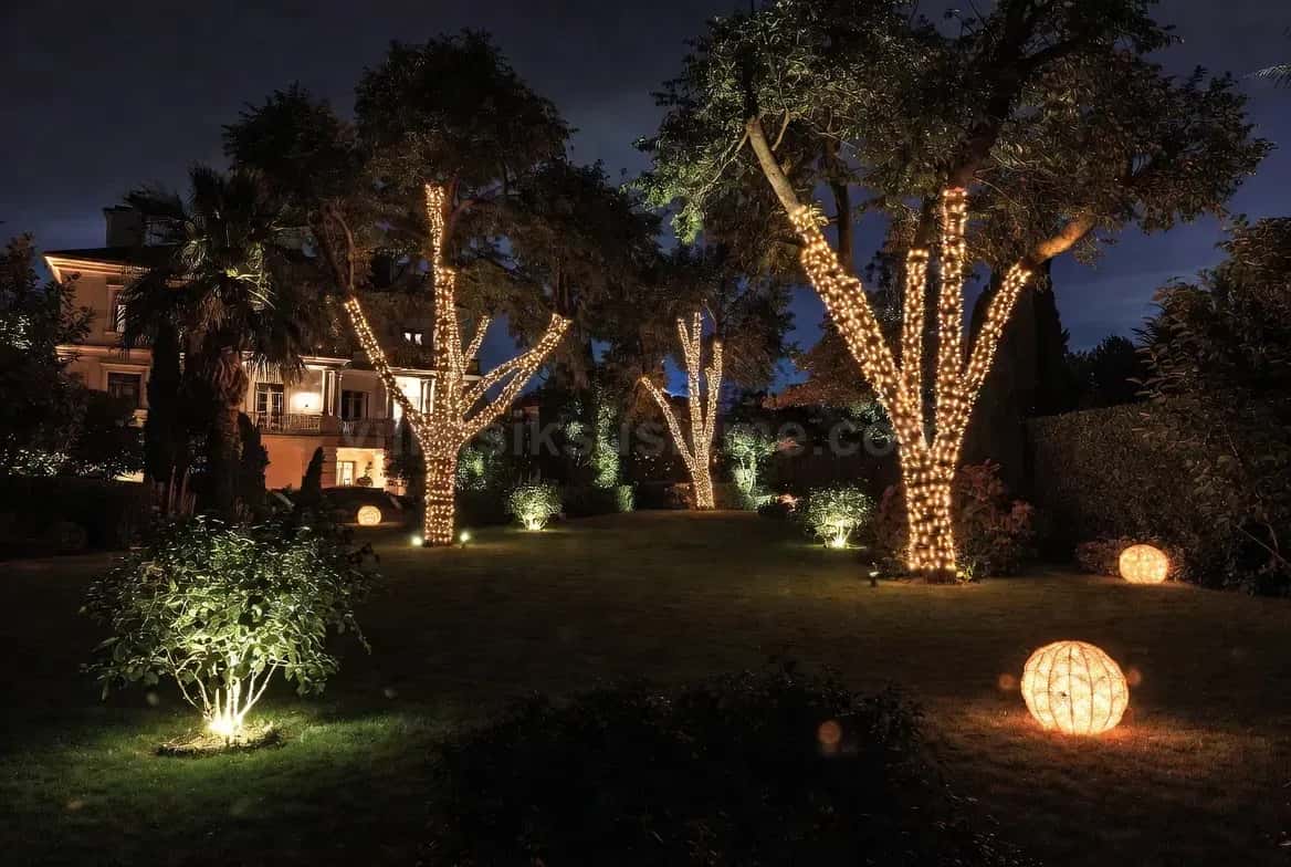 Villa bahçesinde ince gövdeli ağaçlara sarılmış ışık