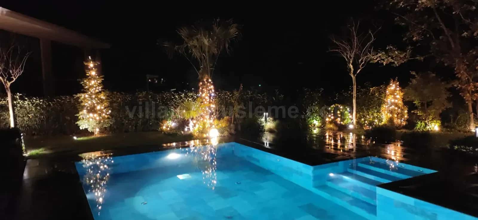 Havuzlu villa bahçesinde ağaç ışıklandırması